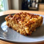 A close-up of a golden-brown slice of baked oatmeal on a grey plate.