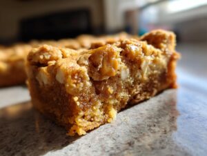 Close-up of a chewy butterscotch blondie with white chocolate chips and caramel swirls.