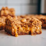 Close-up of a chewy butterscotch blondie with a rich, gooey caramel center oozing out.