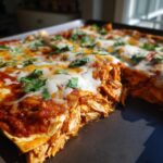 A close-up view of freshly baked chicken enchiladas topped with melted cheese and cilantro.