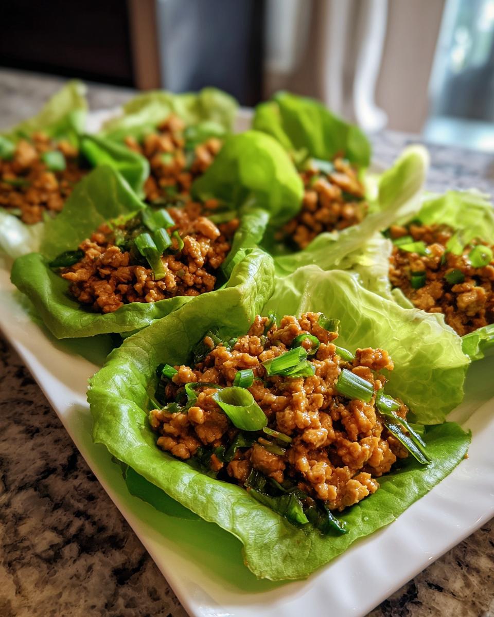 Close-up of delicious chicken lettuce wraps filled with seasoned ground chicken and topped with green onions.