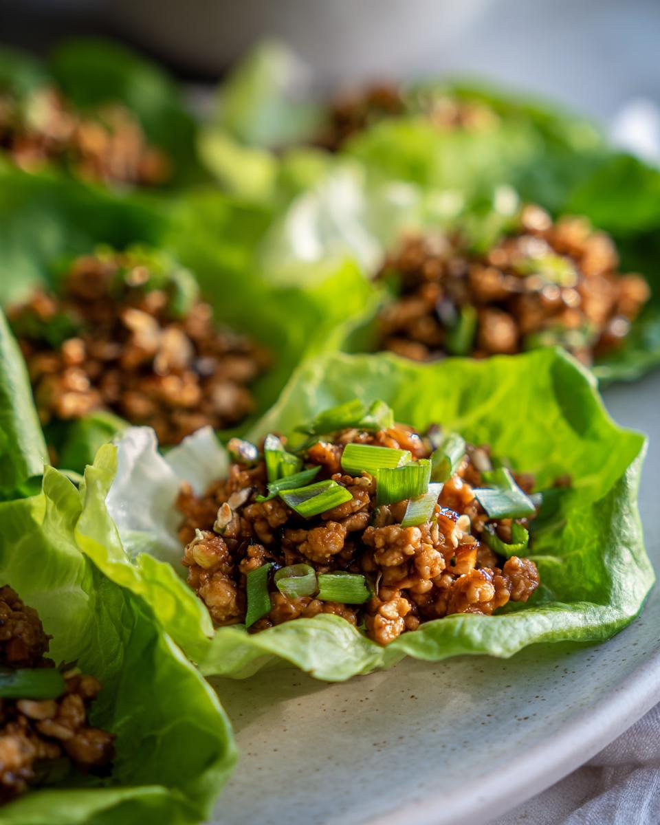 Close-up of delicious chicken lettuce wraps filled with savory ground chicken and topped with fresh green onions.
