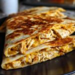 Close-up of a delicious chicken quesadilla, generously filled with shredded chicken and melted cheese.
