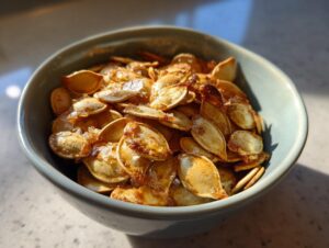 A close-up shot of a bowl filled with golden-brown, crispy roasted pumpkin seeds.