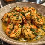 A close-up of succulent garlic butter shrimp scampi, glistening in butter sauce and sprinkled with fresh parsley.