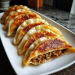 A plate of perfectly pan-fried pork dumplings, showcasing their golden-brown crispy bottoms and juicy filling.
