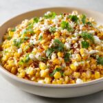 A close-up of a bowl filled with vibrant Mexican street corn salad, topped with crumbled cheese and fresh cilantro.
