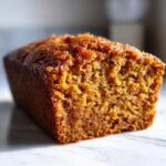 A close-up view of a slice of moist pumpkin bread, showcasing its tender crumb and golden-brown crust.