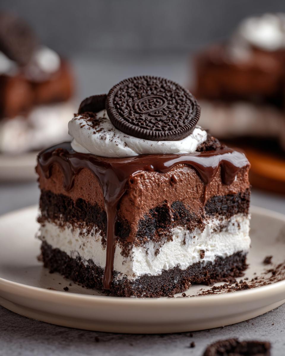 A decadent slice of no-bake chocolate lasagna, layered with chocolate mousse, cream, and cookie crumbs, topped with whipped cream and an Oreo cookie.