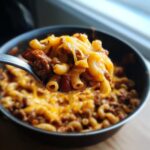 A spoonful of cheesy one pot chili mac with elbow macaroni, ground beef, and kidney beans.