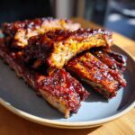 Close-up of delicious oven baked ribs, glistening with a rich BBQ glaze.