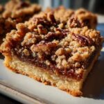 Close-up of a single Pecan Pie Bar with a golden crust, gooey filling, and crunchy pecan crumble topping.