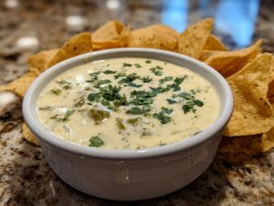 A bowl of creamy Queso Blanco dip topped with fresh cilantro, served with tortilla chips.