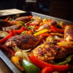 Close-up of seasoned chicken breasts and colorful bell peppers and onions on a baking sheet, ready for sheet pan chicken fajitas.