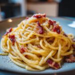 A close-up of a plate of authentic Spaghetti Carbonara, featuring perfectly cooked pasta coated in a creamy sauce with crispy guanciale.