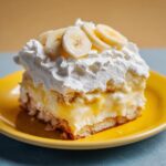 A delicious slice of banana pudding topped with whipped cream and fresh banana slices on a yellow plate.