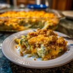 A delicious slice of cheesy broccoli casserole with a crunchy topping on a white plate.
