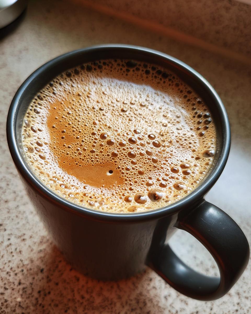 Close-up of a frothy, warm chai latte in a dark mug, perfect for a cozy moment.