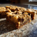 Close-up of a rich, chewy chocolate chip blondie bar with melted chocolate chips.