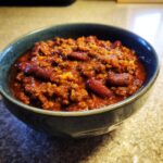A close-up of a bowl filled with steaming Classic Beef Chili, featuring ground beef and kidney beans in a rich sauce.