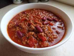 A close-up shot of a bowl of hearty classic chili, featuring ground beef, kidney beans, and a rich tomato sauce.