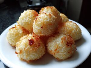 A plate of golden-brown Coconut Ladoo, coated in shredded coconut and lightly toasted.