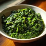 A close-up of a bowl of rich and creamy spinach, seasoned with spices.