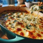A spoonful of hot, bubbly Creamy Spinach Artichoke Dip being lifted, showing a delicious cheese pull.