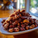 A heaping pile of delicious Crockpot Spiced Nuts, featuring almonds and cashews coated in a sweet and savory spice blend.