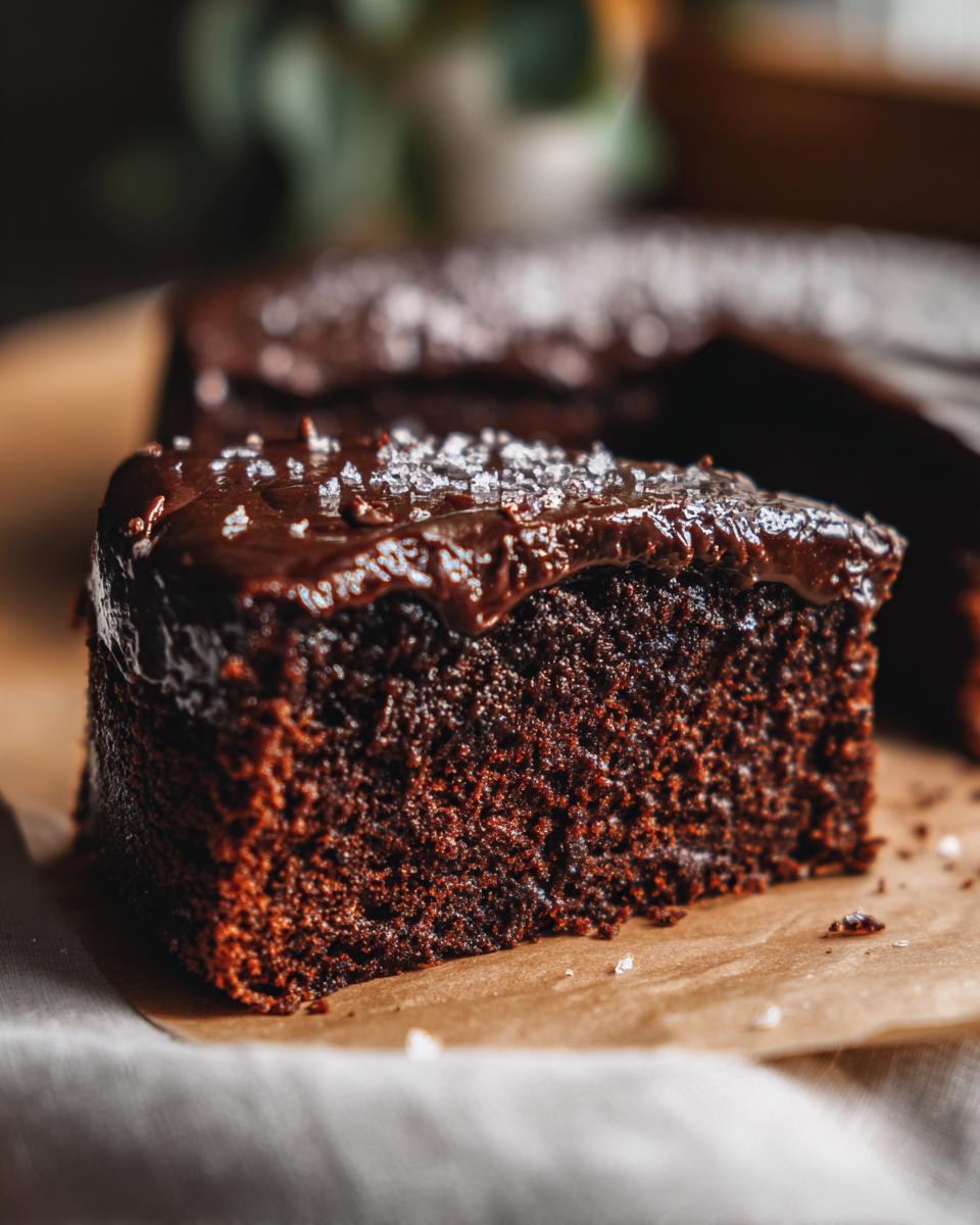 A moist slice of decadent chocolate cake topped with rich ganache and sprinkled with sea salt.