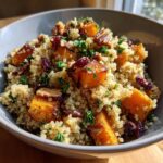 A close-up of a bowl of Fall Harvest Quinoa Salad, featuring quinoa, roasted butternut squash, cranberries, and pecans.