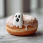 A delicious glazed donut decorated with a cute white ghost topper, perfect for Ghost Donuts.