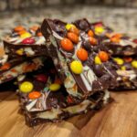 Close-up of stacked Halloween Candy Bark pieces, showcasing dark chocolate, white chocolate swirls, and colorful candy pieces.