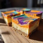 Close-up of Halloween Cheesecake Bars with orange, purple, and teal swirls on a wooden board.