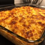 Close-up of a bubbling, golden brown hash brown casserole topped with melted cheese.