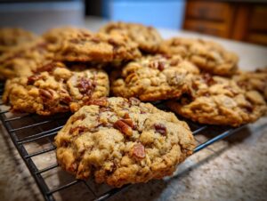 Close-up of freshly baked Maple Pecan Cookies piled on a wire cooling rack, showcasing chunks of pecans.