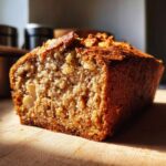 A close-up of a moist Apple Bread loaf with visible chunks of nuts baked into the crumb.