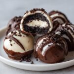 Close-up of delicious Oreo balls, one cut in half showing the creamy center and dark cookie exterior.