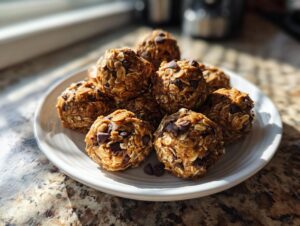 A pile of delicious Peanut Butter Oatmeal Energy Bites studded with chocolate chips on a white plate.