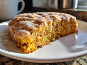 A close-up of a moist Pumpkin Scone drizzled with white glaze, ready to be enjoyed.