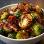 Close-up of a bowl filled with perfectly Roasted Brussels Sprouts with Bacon, showing crispy edges and savory bacon bits.