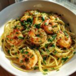 A close-up of a bowl of shrimp scampi, featuring plump shrimp tossed with linguine pasta and fresh parsley.