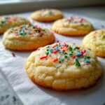 Close-up of freshly baked sugar cookies topped with colorful sprinkles, ready to be enjoyed.