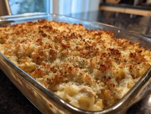 Close-up of a bubbling Turkey Tetrazzini casserole in a glass baking dish, topped with golden-brown breadcrumbs.