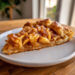 A close-up of a single slice of homemade apple galette, showing flaky crust and caramelized apple filling.