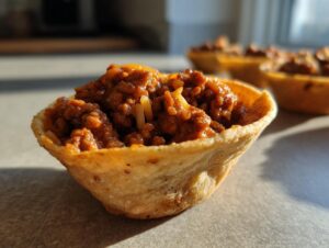 Close-up of a crispy taco shell filled with savory ground beef taco filling and melted cheese.