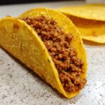Close-up of a crunchy corn tortilla filled with seasoned ground beef for delicious beef tacos.