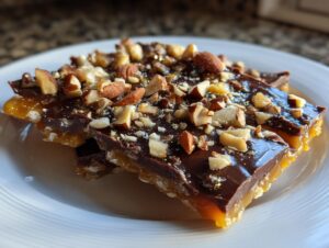 Close-up of rich chocolate toffee topped with chopped almonds and a sprinkle of edible glitter.