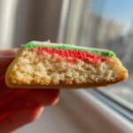 Close-up cross-section showing the soft, layered interior of a Christmas sugar cookies with red and green icing.