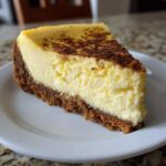 A perfect slice of creamy Eggnog cheesecake with a thick graham cracker crust, dusted with cinnamon.